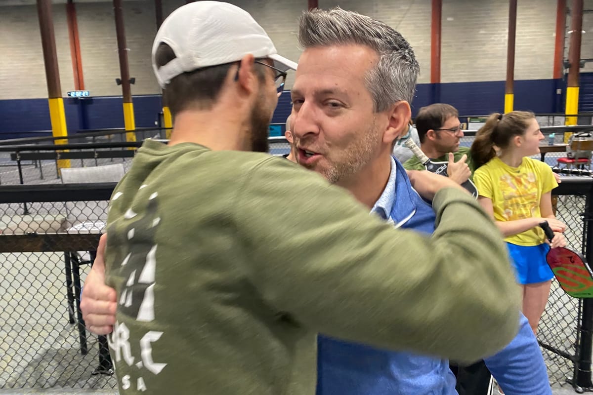 Two players greeting each other with a bear hug beside the courts
